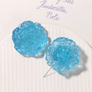 Macro shot of icy blue resin flower charms with textured petals and metal pin base