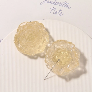 Close-up of translucent light yellow resin daisy earrings on a white ceramic plate