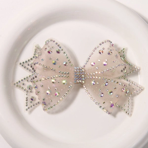 Detail of champagne mesh bow with iridescent rhinestones on a white ceramic tray