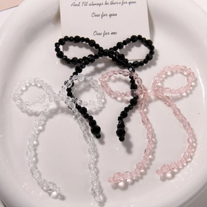 Three crystal beaded bow charms with tassels in black, clear, and pink colors