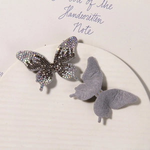 Detailed close-up of sparkling rhinestone butterfly charms with soft gray flocked backing