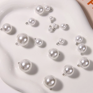 Detail of round white pearl pendants in various sizes with silver metal hanging loops