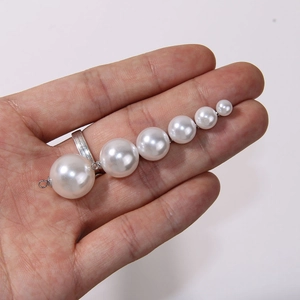 Detail shot of six graduated white pearls on a silver metal base held by a hand