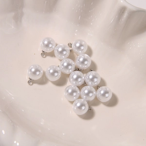 Macro shot of glossy white round pearl pendants with silver loops in a shell dish