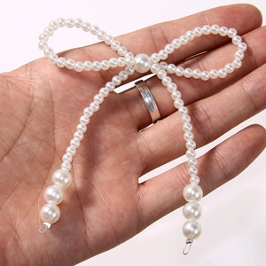Close-up of handmade pearl bow accessory with metallic ring for DIY footwear decor