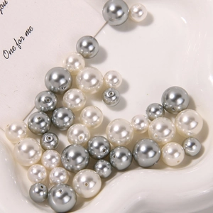 Macro shot of matte white and silver glass pearls with drill holes for DIY jewelry