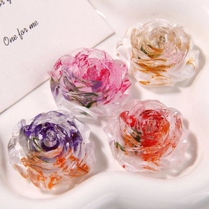 Détail de breloques roses en résine avec fleurs séchées dans un plateau coeur en céramique