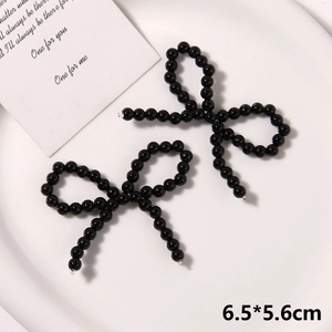 Detailed view of handmade black bead woven bow accessories on a white ceramic tray