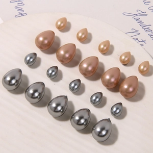 Water-drop faux pearls in silver and champagne gold on a white tray for DIY jewelry