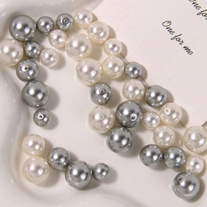 Macro view of matte white and grey glass pearls for DIY jewelry making in a tray