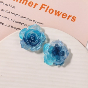 Close-up of DIY glitter blue resin rose flower accessories on a white plate