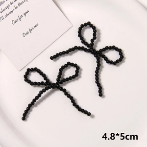 Detailed view of handmade black beaded bow charm accessory on a white ceramic plate