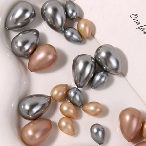 Macro shot of silver and champagne pearl drop beads in a white ceramic tray for DIY jewelry