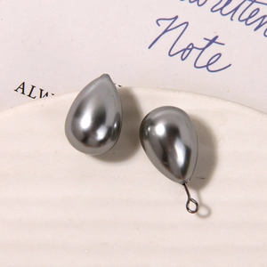 Detailed view of dark grey teardrop pearls on a ceramic dish for DIY jewelry making