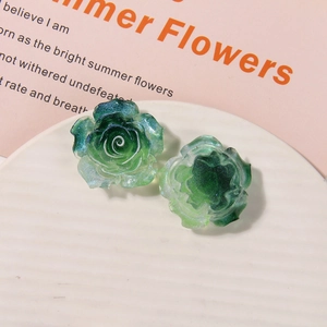 Macro detail of green resin rose charm with gold glitter finish for DIY crafts