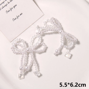 Detail of handmade pearl bow charms with hanging crystal pendants on a tray