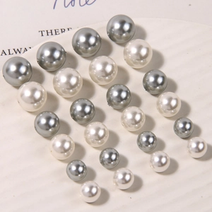 Macro shot of matte grey and cream glass pearls on a white display tray for DIY jewelry