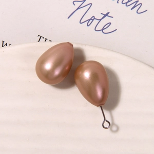 Macro shot of elegant champagne teardrop pearls with metal ring on white tray