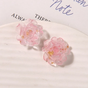 Détails de boucles d'oreilles fleurs en résine rose avec feuille d'or sur plateau