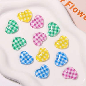 Close-up of colorful gingham checkered heart-shaped resin charms on a white tray