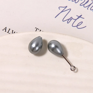 Macro shot of silver-gray teardrop beads for DIY jewelry making on white ceramic