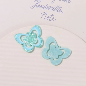 Detailed macro view of mint green and pearl blue acrylic butterfly shoe charms with glitter
