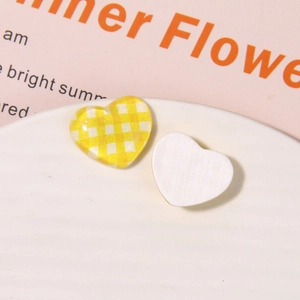 Detailed macro view of heart-shaped resin DIY charms with yellow gingham and white textures