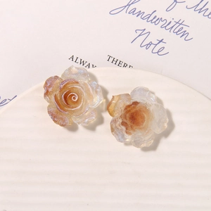 Close-up of translucent luminous rose charms with amber gradient and glitter details