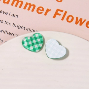 Macro view of green and white checkered heart-shaped resin charms on a ceramic plate