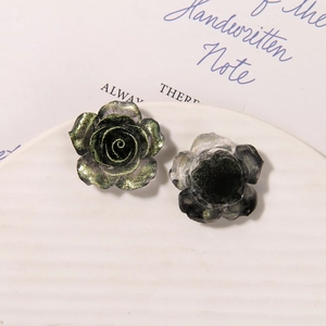 Macro shot of dark green luminous rose resin charms with glitter on ceramic plate