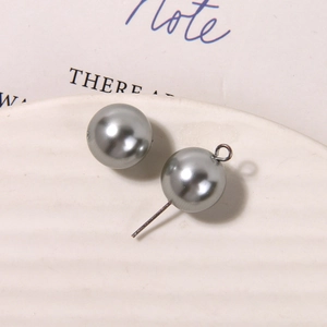 Macro shot of grey matte glass pearls with silver metal hooks on a white textured tray