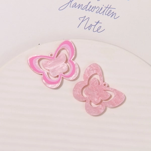 Detailed view of pink acrylic butterfly charms with layered patterns and marble texture