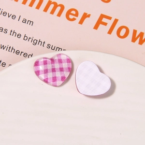 Macro view of pink and purple gingham heart resin charms with glitter on a white plate