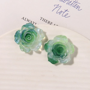 Close-up of green resin rose earrings with sparkling glitter and translucent petals