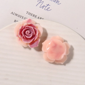 Macro detail of resin rose and camellia charms with matte and glossy textures for DIY