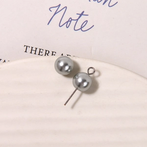 Macro detail of matte silver-grey pearl beads with silver metal pin on a white tray