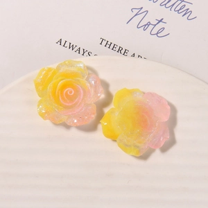 Macro detail of yellow-pink gradient resin rose charms with sparkling glitter finish