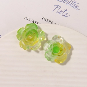 Detailed macro view of two translucent yellow-green resin rose charms with golden foil accents