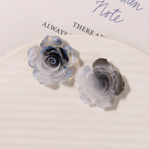 Macro shot of resin luminous rose charms with blue gradient and glitter on a white tray