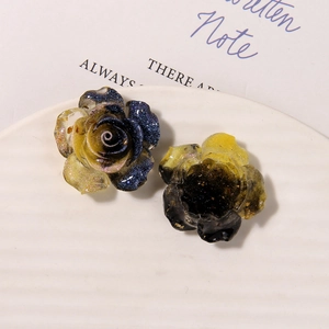 Macro detail of resin rose charms with yellow-to-blue gradient and sparkly gold glitter
