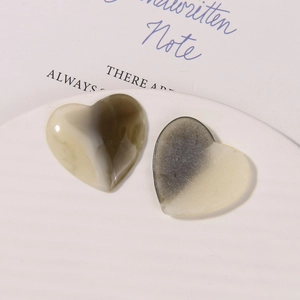 Dettaglio macro di ciondoli a cuore in resina con trama marmorizzata grigio e beige per accessori fai da te