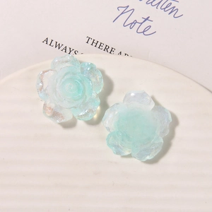 Close-up of translucent aurora resin rose charms with a shimmering finish for DIY crafts