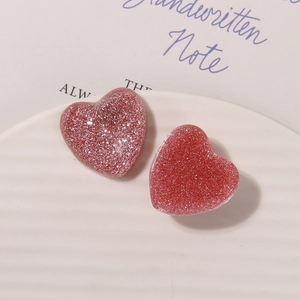 Vue macro de breloques cœur en résine à paillettes rouge et rose pour accessoires de cheveux