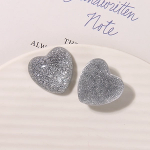 Gros plan de charms en résine cœur pailleté argenté sur une assiette en céramique