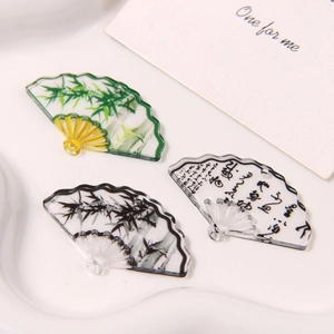 Macro shot of acrylic Chinese fan charms with bamboo ink painting and calligraphy motifs