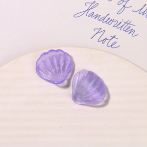 Macro shot of purple translucent shell-shaped acrylic charms with fine glitters for DIY crafts