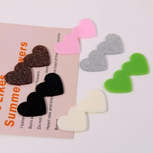 Flat lay of colorful acrylic double heart charms in solid and glitter finishes for DIY crafts