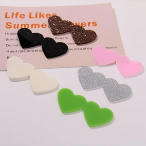 Macro detail of acrylic double heart charms in glitter and solid colors for DIY crafts