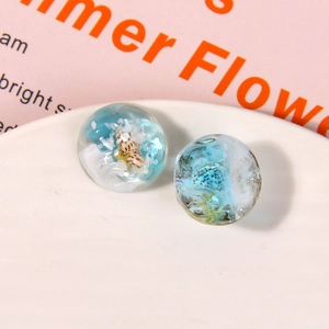 Macro detail of ocean-themed resin sphere charms with seashells and golden starfish