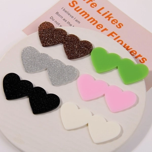DIY acrylic heart-shaped accessories with glitter and smooth finish on a white plate